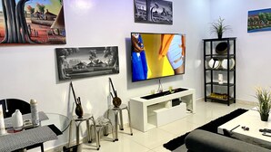 Un salon moderne doté d’un téléviseur à écran plat, d’une table basse, d’un canapé et d’un coin repas avec des chaises et une table.