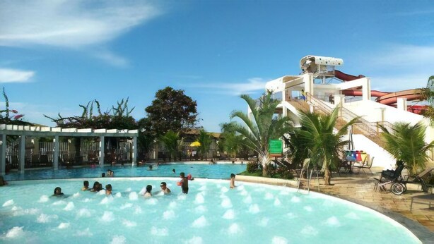 A pool area with people swimming and a water slide structure. - Lindo Flat Localizado no Lacqua Diroma V (GO)