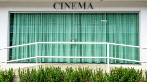 A building with a sign that reads "CINEMA" above a large window with green curtains. - Lindo Flat Localizado no Lacqua Diroma V (GO)
