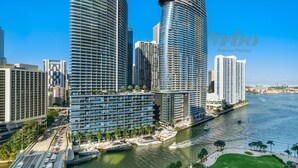 Ein modernes Hochhaus-Hotel mit Blick auf das Wasser, das eine geschwungene Fassade, mehrere Balkone und einen Yachthafen mit Booten zeigt.
