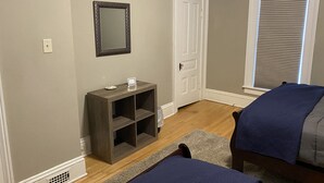 A bedroom with a wooden bed, a bedside table, a mirror, a door, and a window with blinds. - Close to Downtown & UWEC (Eau Claire)