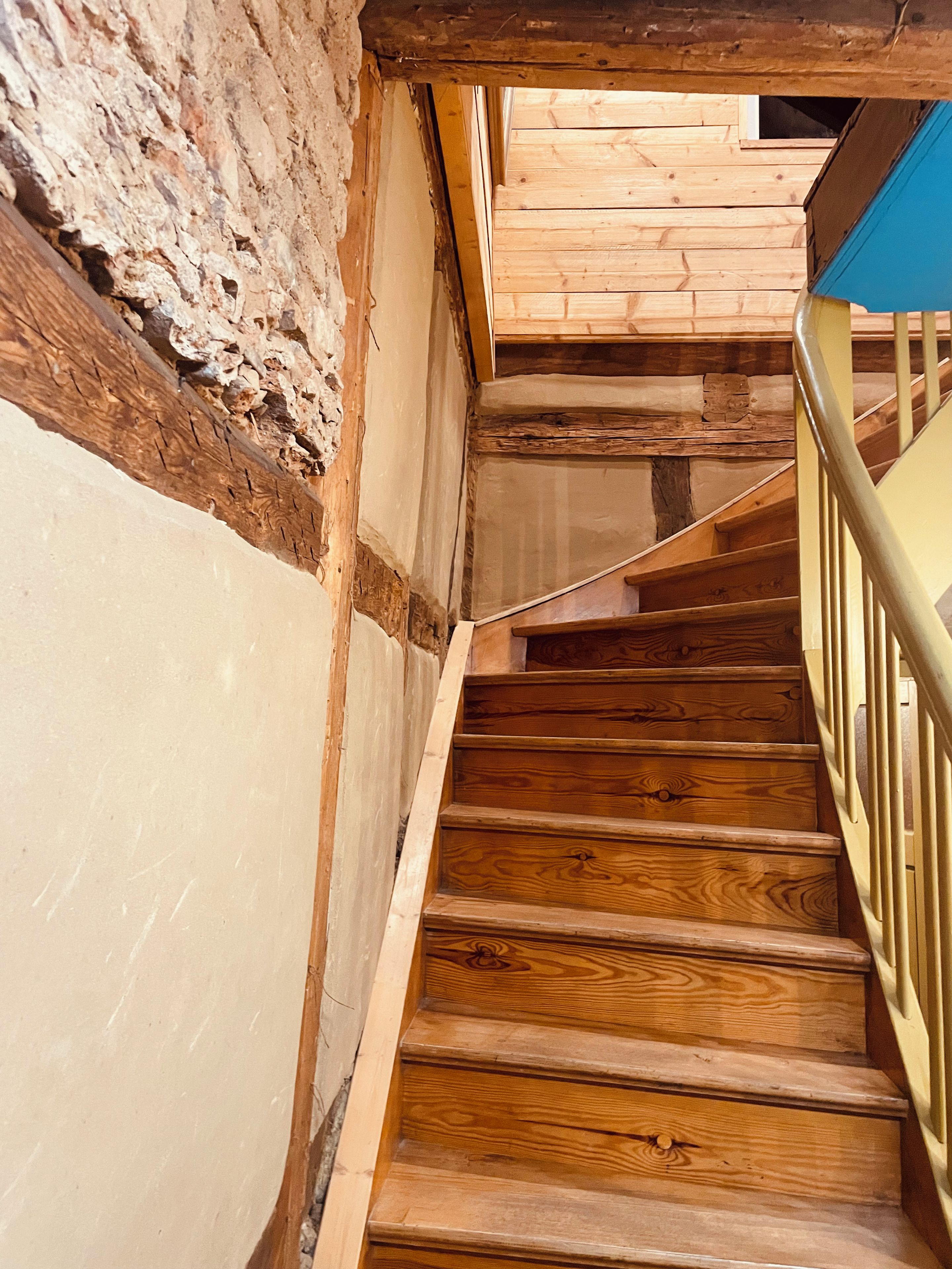 A wooden staircase with a metal handrail, leading to a room with wooden walls and a window.