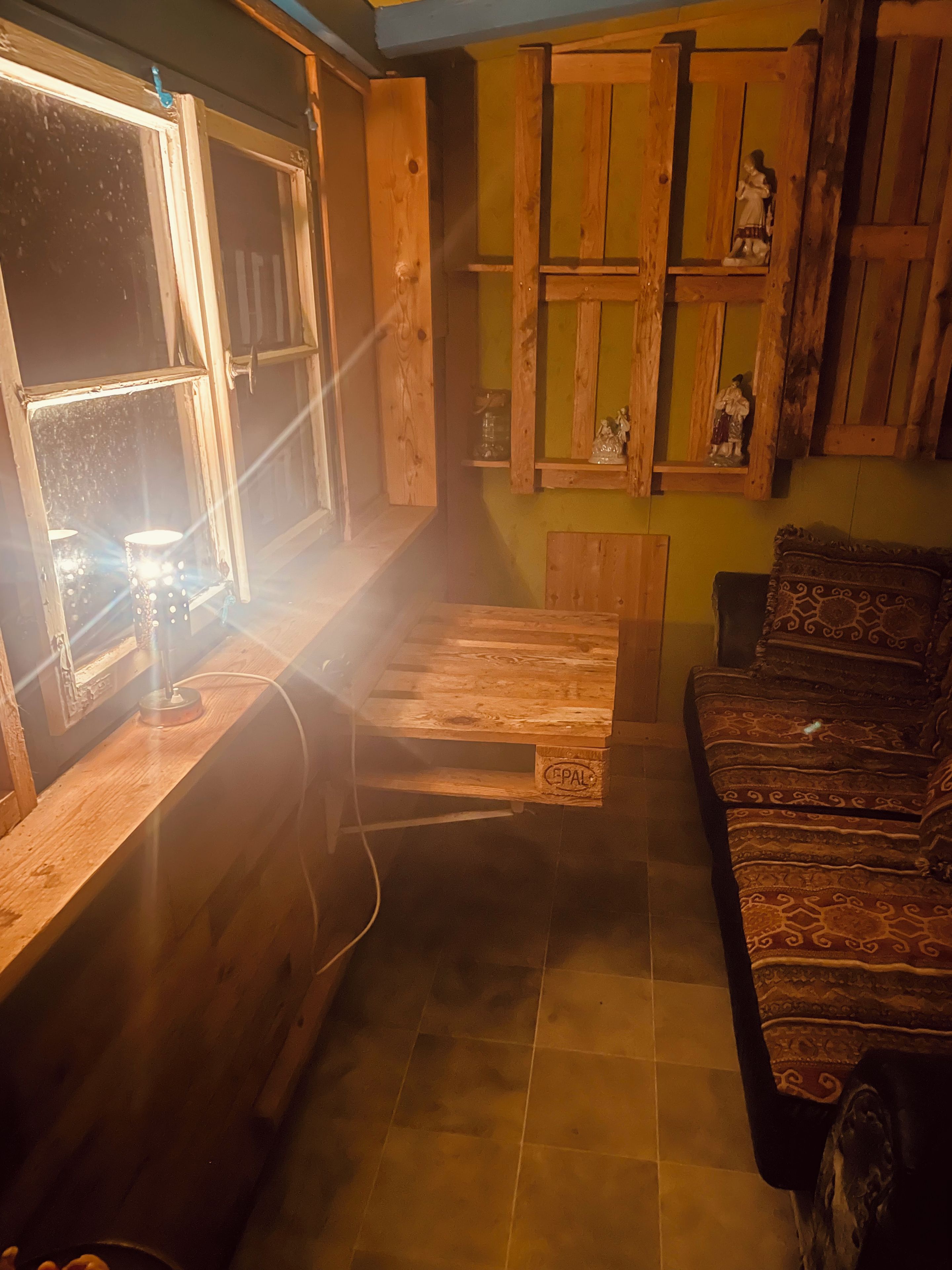 Ein gemütliches Zimmer mit Holzboden, einer Holzbank, einer gepolsterten Couch und einem Fenster mit einer Leuchte.