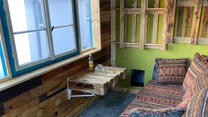 A room with a wooden bench, a sofa with patterned cushions, a window with a view, and a wooden wall. - Vintage Home 55 (Eisenach)