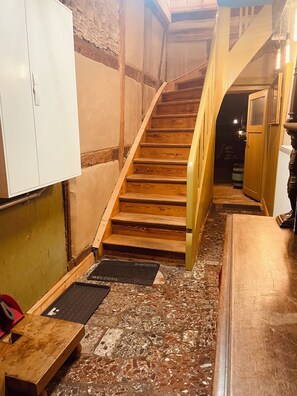 A wooden staircase with a handrail, a white cabinet, and a welcome mat at the bottom.
