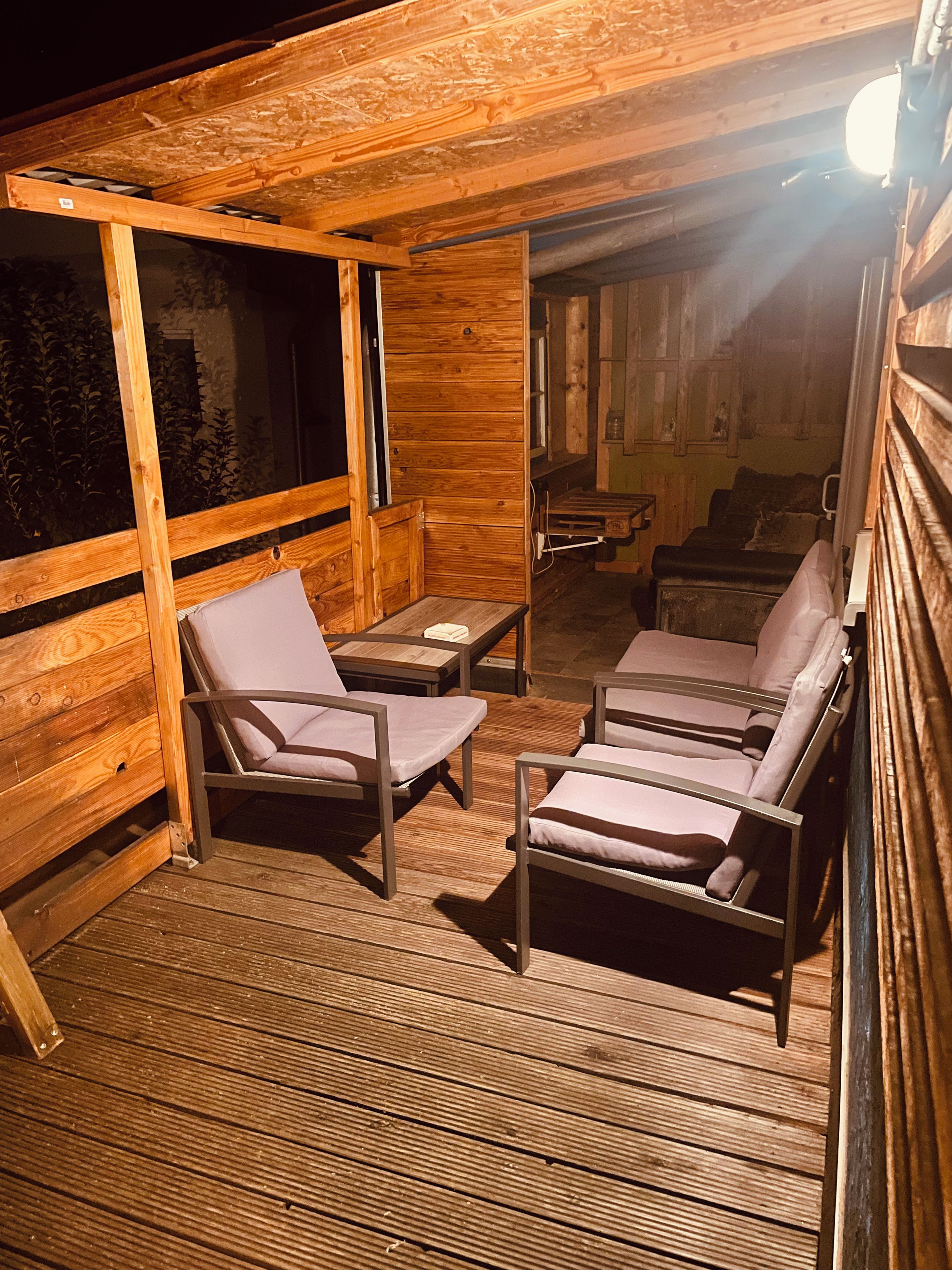 A wooden deck with two lounge chairs and a small table.