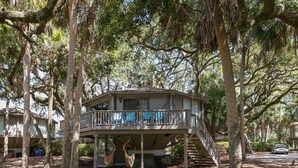A treehouse with a balcony, surrounded by tall trees and a clear sky. - PEACEFUL SEABROOK ISLAND TREEHOUSE WITH LAGOON VIEWS (Seabrook Island)