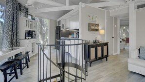 A spacious kitchen with modern appliances, a dining area with a long table and benches, and a staircase leading to an upper level. - PEACEFUL SEABROOK ISLAND TREEHOUSE WITH LAGOON VIEWS (Seabrook Island)