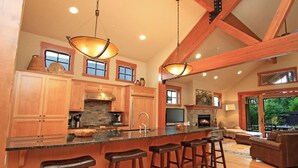 A spacious kitchen with a large island, wooden bar stools, and a fireplace. - EV Charger! HOT TUB! Perfect family getaway in the ❤️ of Suncadia! (Cle Elum)