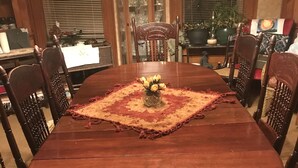 A wooden dining table with a glass vase of yellow flowers, surrounded by wooden chairs. - Cooperstown Dreams Park Baseball Rental All Star Village Catskills Oneonta (Mount Vision)
