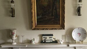 A fireplace mantel with a framed painting, a small house model, and decorative items. - Cooperstown Dreams Park Baseball Rental All Star Village Catskills Oneonta (Mount Vision)