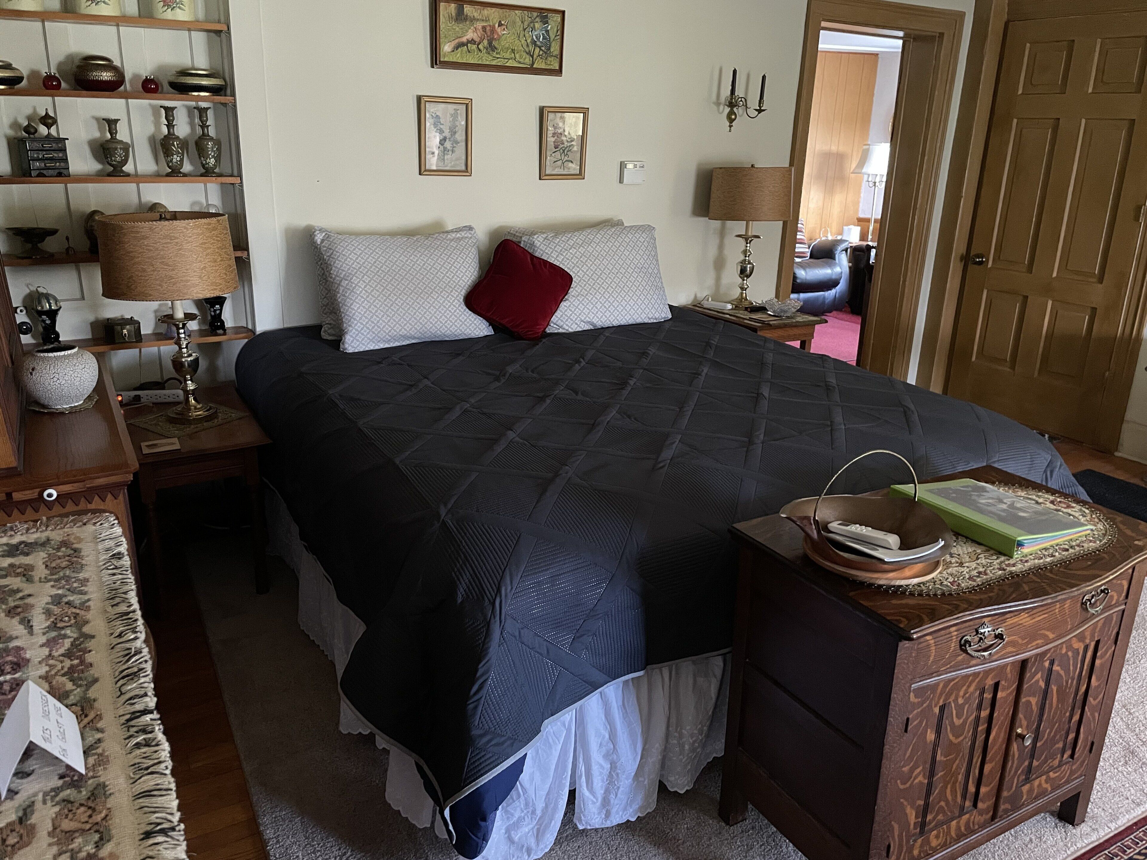 Un dormitorio ordenado con una cama grande, una mesita de noche, una lámpara y un aparador.