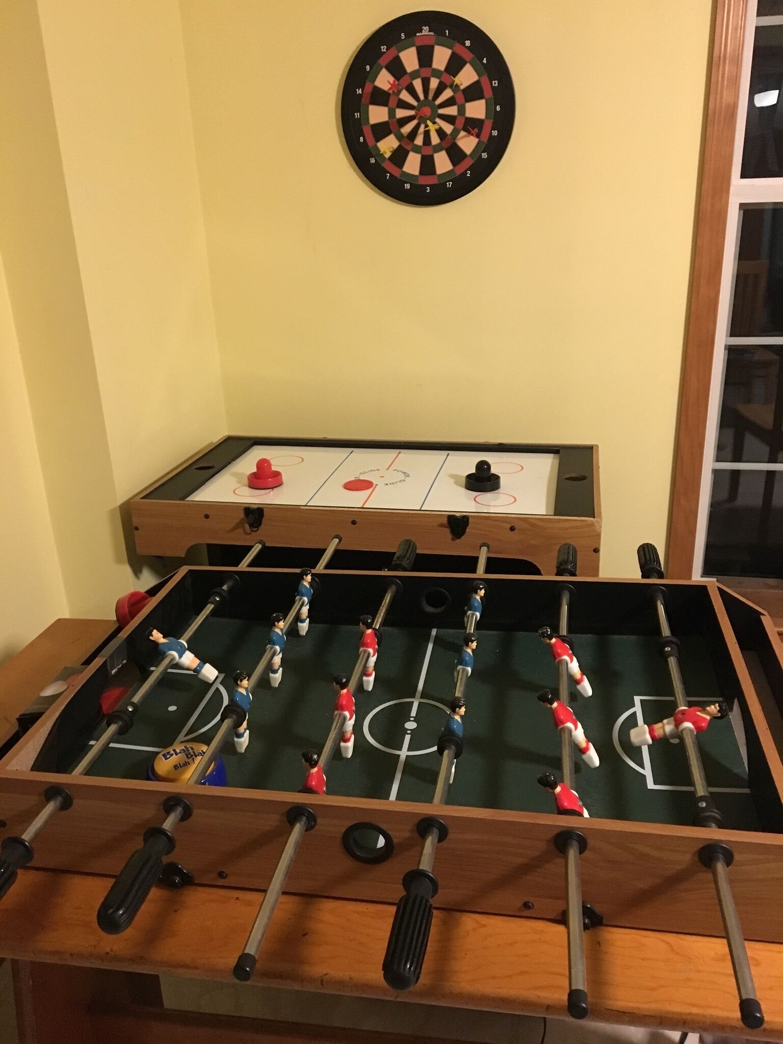 Una mesa de futbolín con un dardo colgado encima.