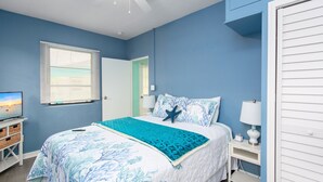 A bedroom with a bed, a nightstand, a lamp, a TV, and a window with blinds.