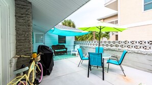 A patio with a table and chairs, a bicycle, and a grill.