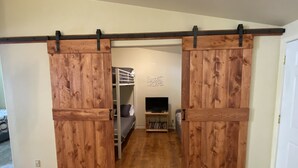 Ein Zimmer mit Etagenbett, Fernseher und Bücherregal.