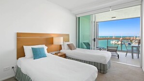 A hotel room with two beds, a balcony with a view of the marina, and a table with chairs. - 2 Bedroom (Whitsunday)