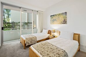 Ein Hotelzimmer mit zwei Betten, einem Balkon mit Aussicht und einem Bild an der Wand.