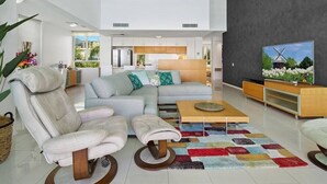 Una sala de estar moderna con un sofá, sillones, una mesa de centro y una televisión.