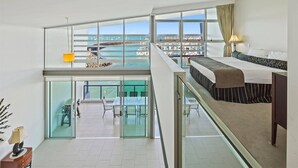 Ein Hotelzimmer mit Balkon, einem Bett, einem Schreibtisch und Blick auf den Yachthafen.
