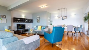 Una sala de estar moderna con un sofá, una mesa de centro, un televisor y un comedor con sillas y una mesa.