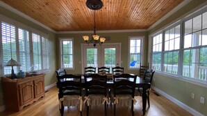 A dining room with a wooden ceiling, large windows, and a chandelier. - Douglas Lake Waterfront Estate (Sevierville)