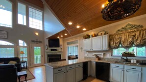 A spacious kitchen with white cabinets, a large island, and a wooden ceiling. - Douglas Lake Waterfront Estate (Sevierville)