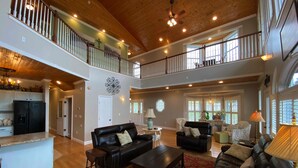 A spacious living area with a high ceiling, wooden beams, and a balcony. - Douglas Lake Waterfront Estate (Sevierville)