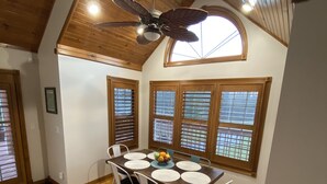 A dining area with a wooden table, white chairs, and a ceiling fan. - Lake house with boat ramp access across the street & tons of boat parking space. (Monticello)
