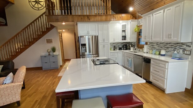 A spacious kitchen with a large island, wooden flooring, and a staircase leading to an upper level. - Lake house with boat ramp access across the street & tons of boat parking space. (Monticello)