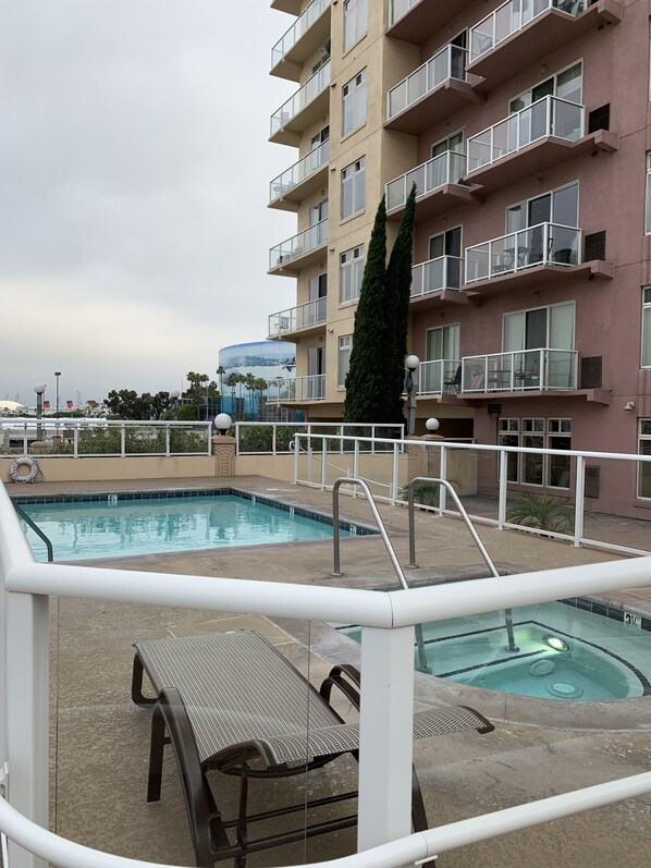 A swimming pool area with a lounge chair and a hot tub.