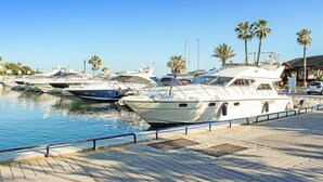 A marina with several yachts docked, a paved walkway, and palm trees in the background. - 2 bedroom awesome apartment in Marbella (Marbella)