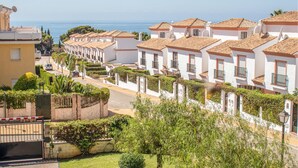 A row of white buildings with terracotta roofs, a paved street, and a view of the sea. - 2 bedroom awesome apartment in Marbella (Marbella)