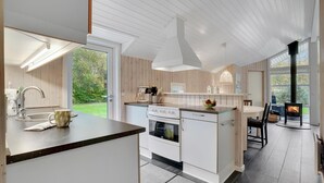 A modern kitchen with a central island, a stove, and a dining area with a view of the outdoors.