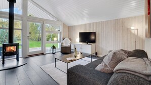 A cozy living room with a fireplace, a sofa, a TV, and a dining area.