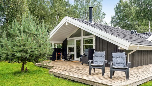A modern house with a deck, a chimney, and outdoor seating.