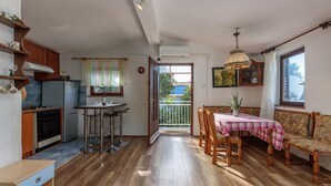 A kitchen with a dining area, wooden flooring, and a view through an open door. - Awesome apartment in Klenovica with WiFi (Klenovica)