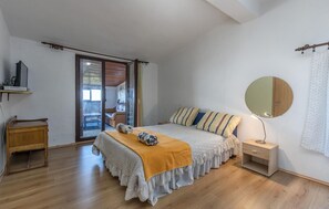 Un dormitorio con cama, mesita de noche, espejo y puerta corrediza de vidrio que da a un balcón.