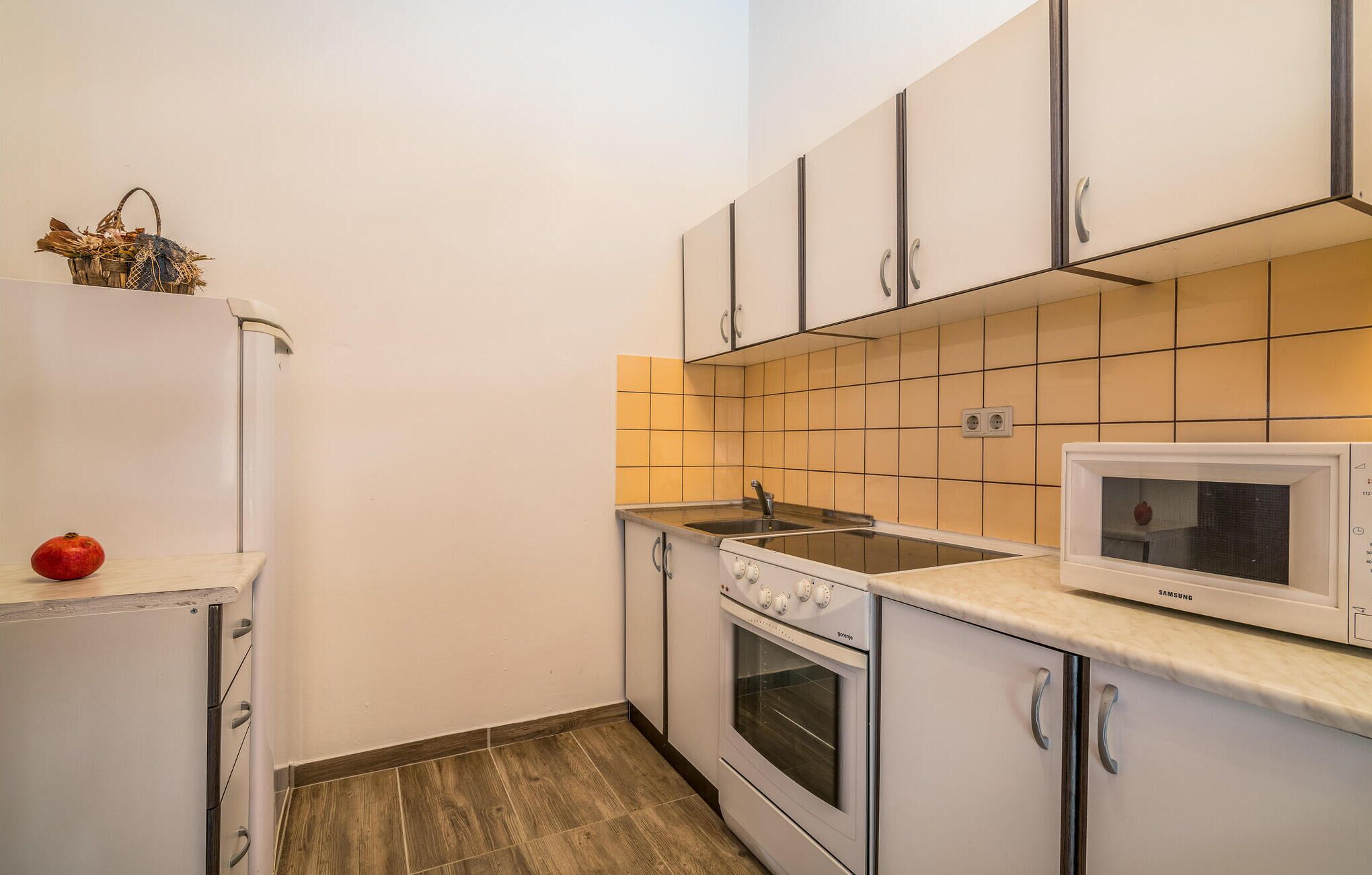 A compact kitchen with white cabinets, a built-in oven, a microwave, and a sink.