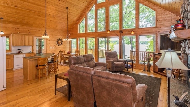 A spacious living area with a high ceiling, wooden walls, and large windows. There is a dining area with a table and chairs, and a seating area with sofas. - Private, family friendly lake home w/sandy beach in Crosslake on Pine Lake (Crosslake)