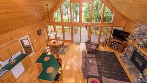A cozy cabin interior with a dining area, seating, a fireplace, and large windows offering a view of the outdoors. - Private, family friendly lake home w/sandy beach in Crosslake on Pine Lake (Crosslake)