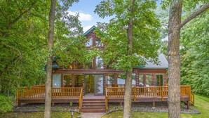 A cabin with a wooden deck, a covered porch, and a staircase leading to the entrance. - Private, family friendly lake home w/sandy beach in Crosslake on Pine Lake (Crosslake)