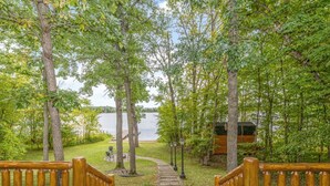 A wooden deck leading to a lake with trees and a small building in the background. - Private, family friendly lake home w/sandy beach in Crosslake on Pine Lake (Crosslake)