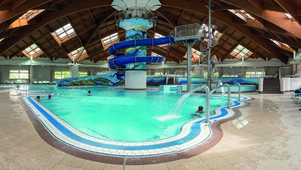 En indendørs swimmingpool med en stor rutsjebane og flere baner.