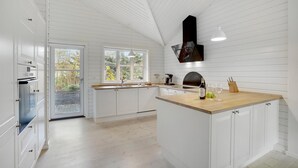 A kitchen with white cabinetry, a wooden countertop, and a built-in oven. - 3 bedroom beautiful home in Gilleleje (Gilleleje)