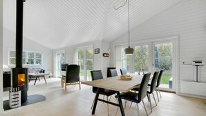 A spacious room with a large dining table, chairs, and a wood-burning stove. - 3 bedroom beautiful home in Gilleleje (Gilleleje)