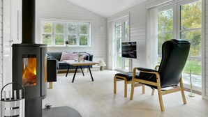 A cozy room with a fireplace, a sofa, a chair, and a TV. - 3 bedroom beautiful home in Gilleleje (Gilleleje)