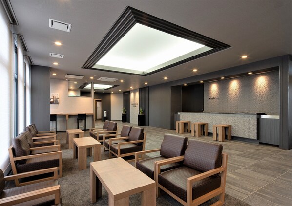 A modern hotel lobby with a reception desk, seating area, and a skylight.