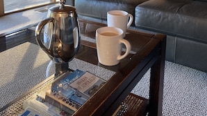 A cozy living room with a leather sofa, a coffee table with a kettle and two mugs, and a window with a view of trees. - Bush Farm overlooking quiet valley  (Clarence Town)