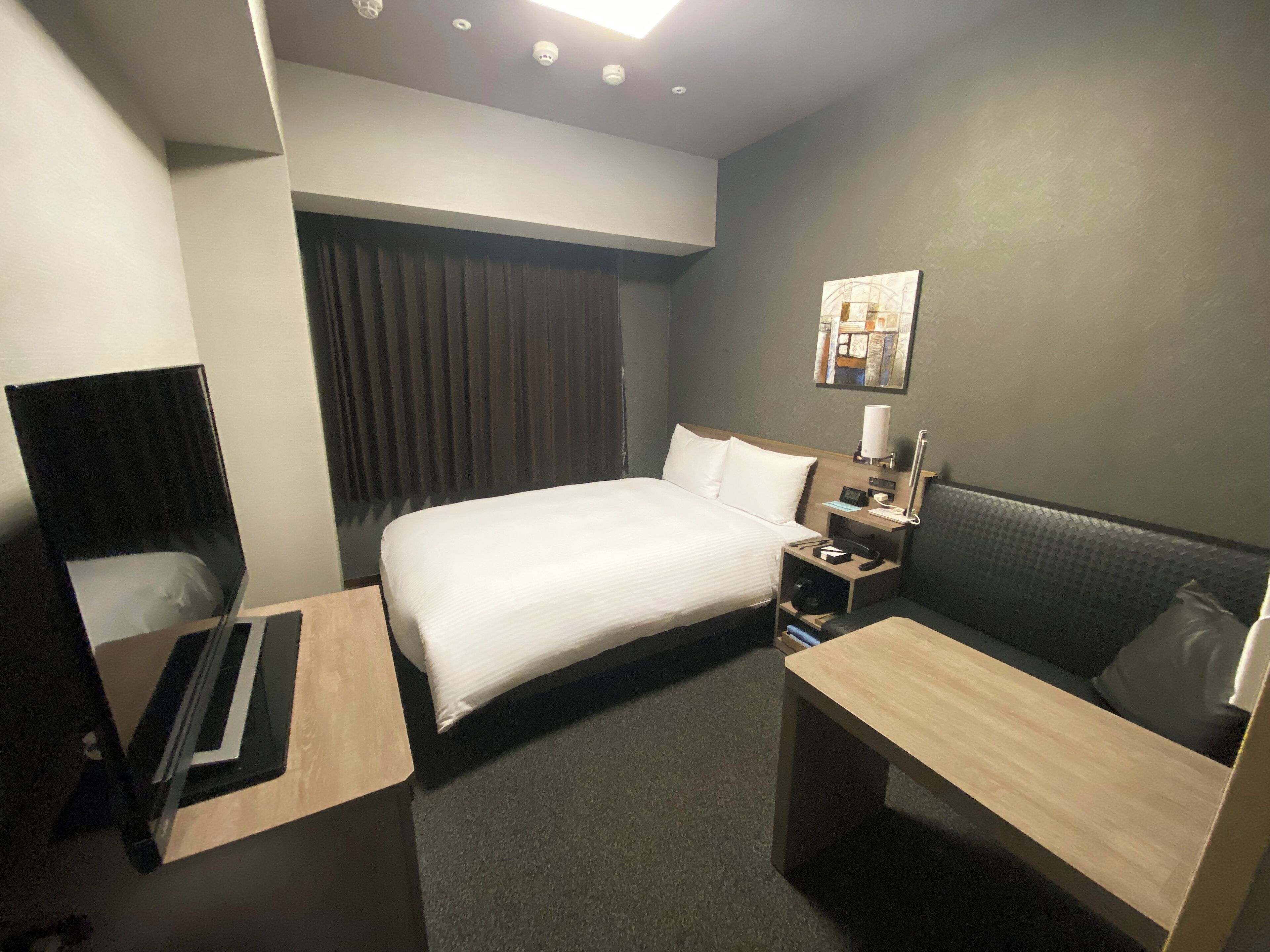 Hotellihuone, jossa on sänky, yöpöytä, työpöytä ja oleskelualue.